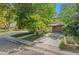 Charming home with a brick facade, lush green lawn, mature trees, and a convenient driveway leading to the garage at 2518 S Patton Ct, Denver, CO 80219