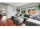 Cozy living room featuring an expansive gray sectional couch, dark hardwood floors, and many windows at 2021 Eliot St, Denver, CO 80211