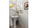 Charming powder room features a pedestal sink, tiled floors, a sleek mirror, and a decorative art piece at 3133 Blake St # 3, Denver, CO 80205
