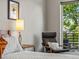 Bedroom with a comfy chair, side table with lamp, a large bed, and balcony access with tree views at 3133 Blake St # 3, Denver, CO 80205