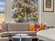 A living room has a window view of a large leafy tree and modern art on the walls at 3133 Blake St # 3, Denver, CO 80205