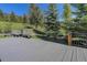 Backyard deck offers seating and views of the manicured lawn and mature trees at 96 Carolyn Rd, Evergreen, CO 80439