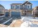 Two-story house with blue siding, two-car garage, and snowy front yard at 7097 S Patsburg Way, Aurora, CO 80016