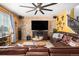 Spacious living room with a stone accent wall, leather furniture, and a large TV at 7097 S Patsburg Way, Aurora, CO 80016