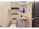Well-lit powder room with pedestal sink, open shelf, and decorative mirror at 4689 Tanner Peak Trl, Brighton, CO 80601