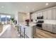 Modern kitchen featuring an island with seating, stainless steel appliances, and gray cabinets at 9099 Sedalia St, Commerce City, CO 80022