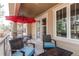 Relax on this covered deck, featuring stylish furniture and an inviting red umbrella at 7132 S Irvington Ct, Aurora, CO 80016