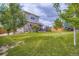 A beautifully landscaped backyard features a lush lawn, mature trees, and a charming patio area at 24748 E Layton Pl, Aurora, CO 80016