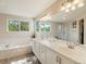 Bathroom with dual sinks, soaking tub, and large window providing natural light at 6293 Braun Cir, Arvada, CO 80004