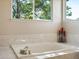 Bright bathroom featuring a soaking tub with tile surround and large window providing natural light at 6293 Braun Cir, Arvada, CO 80004