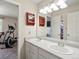 Bright bathroom featuring a double sink vanity and an exercise machine just outside the doorway at 6293 Braun Cir, Arvada, CO 80004