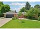 Charming brick home with a well-manicured lawn, lush landscaping, and inviting front porch with red chairs at 721 Park Ln, Lakewood, CO 80214