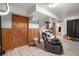 Spacious basement featuring wood-look flooring, wood paneled walls, drop ceiling, and an outdated recliner at 7066 Jennie Dr, Denver, CO 80221