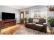 Inviting living room featuring hardwood floors, a leather sofa, natural light, and wood-trimmed front door at 7066 Jennie Dr, Denver, CO 80221