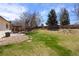 Expansive backyard featuring lush green grass, mature trees, and a cozy covered patio at 4627 S Norfolk Way, Aurora, CO 80015