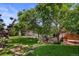 Landscaped backyard features a patio area, a manicured lawn, and mature trees for privacy at 4627 S Norfolk Way, Aurora, CO 80015