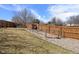 Fenced-in backyard with grass, mature trees, and a secure area for pets at 4627 S Norfolk Way, Aurora, CO 80015