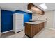 A simple kitchenette featuring tile countertops and a full-sized refrigerator against a blue accent wall at 4627 S Norfolk Way, Aurora, CO 80015