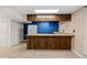 A simple kitchenette featuring tile countertops and a full-sized refrigerator against a blue accent wall at 4627 S Norfolk Way, Aurora, CO 80015