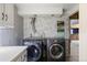 Bright laundry room with modern washer and dryer, floral wallpaper, and ample cabinet space at 4627 S Norfolk Way, Aurora, CO 80015