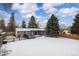 Spacious backyard with snow-covered lawn, deck, and wooden fence at 670 S Oswego St, Aurora, CO 80012