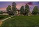 A stunning backyard featuring lush grass, mature trees, a pergola, a water feature, and an outdoor gazebo at 6940 Saddleback Ave, Firestone, CO 80504