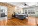 Bright bedroom featuring a wood accent wall, ceiling fan, and shuttered windows at 6940 Saddleback Ave, Firestone, CO 80504
