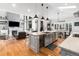 Bright, open kitchen with stainless steel appliances, light grey cabinetry, an island, and hardwood floors at 6940 Saddleback Ave, Firestone, CO 80504