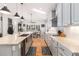 Long shot of updated open concept kitchen with island including bar stool seating, light blue cabinets, and hardwood floors at 6940 Saddleback Ave, Firestone, CO 80504