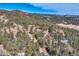 Panoramic aerial shot shows property nestled within a lush forest with mountain views at 21437 Alta Dr, Morrison, CO 80465