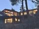 Modern home featuring a deck with large windows and nestled among trees at dusk at 21437 Alta Dr, Morrison, CO 80465