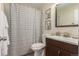 Bright bathroom featuring a striped shower curtain and wooden vanity with updated sink at 10370 Routt St, Westminster, CO 80021