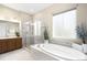 Bathroom featuring a bathtub with stone tiling, a separate shower, and wooden cabinets at 15779 W 83Rd Pl, Arvada, CO 80007