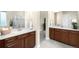 Bathroom featuring dual sinks, wooden cabinets, and a separate doorway to another room at 15779 W 83Rd Pl, Arvada, CO 80007