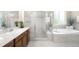 Bathroom featuring a bathtub with stone tiling, a separate shower, and wooden cabinets at 15779 W 83Rd Pl, Arvada, CO 80007