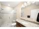 Bright bathroom featuring a glass shower, granite counters, and neutral tile at 15779 W 83Rd Pl, Arvada, CO 80007