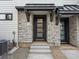 Inviting front entrance with a modern door, stone accents, and concrete steps at 2042 S Holly St # 3, Denver, CO 80222