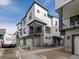 Modern townhome showcases a sleek design with stone accents and attached garages under a blue sky at 2042 S Holly St # 3, Denver, CO 80222