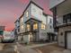 Modern townhome at dusk shows its sleek design with stone accents, attached garages, and glowing windows at 2042 S Holly St # 3, Denver, CO 80222