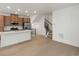 Open-concept living room showcasing hardwood floors, staircase with dark railings, and a kitchen island with a sink at 2042 S Holly St # 3, Denver, CO 80222