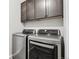 Laundry room showcasing modern grey cabinets over a front loading washer and dryer set at 1702 Metcalf Dr, Erie, CO 80516