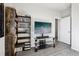 Living room featuring a TV, entertainment center, modern grey hardwood floors, and a dark brown bookcase at 1702 Metcalf Dr, Erie, CO 80516