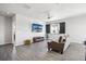 Bright living room with modern ceiling fan, stylish gray floors, and an entertainment center with a large screen TV at 1702 Metcalf Dr, Erie, CO 80516
