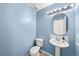 Powder bathroom featuring blue walls, a pedestal sink, round mirror and tile flooring at 21562 E 47Th Ave, Denver, CO 80249