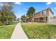 Well-maintained front lawn with mature trees and a sidewalk at 21562 E 47Th Ave, Denver, CO 80249
