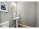 Elegant powder room featuring pedestal sink, oval mirror, and modern lighting fixture at 14025 Blue River Trl, Broomfield, CO 80023