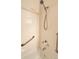 Close-up of the tiled shower showcasing a handheld sprayer and safety bars for accessibility at 3231 E 102Nd Pl, Thornton, CO 80229