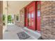 View of brick front porch with a red front door and matching storm door at 3653 E 133Rd Ct, Thornton, CO 80241
