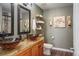 This is a bathroom with a double vanity featuring elegant vessel sinks and attractive fixtures with a decorative shelf above the toilet at 5671 Raleigh Cir, Castle Rock, CO 80104