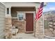 Inviting front porch features stone columns and cozy seating with an American flag at 5671 Raleigh Cir, Castle Rock, CO 80104